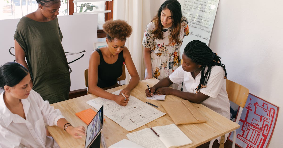 Diverse team collaborates on a project using digital and paper resources in a bright office.
