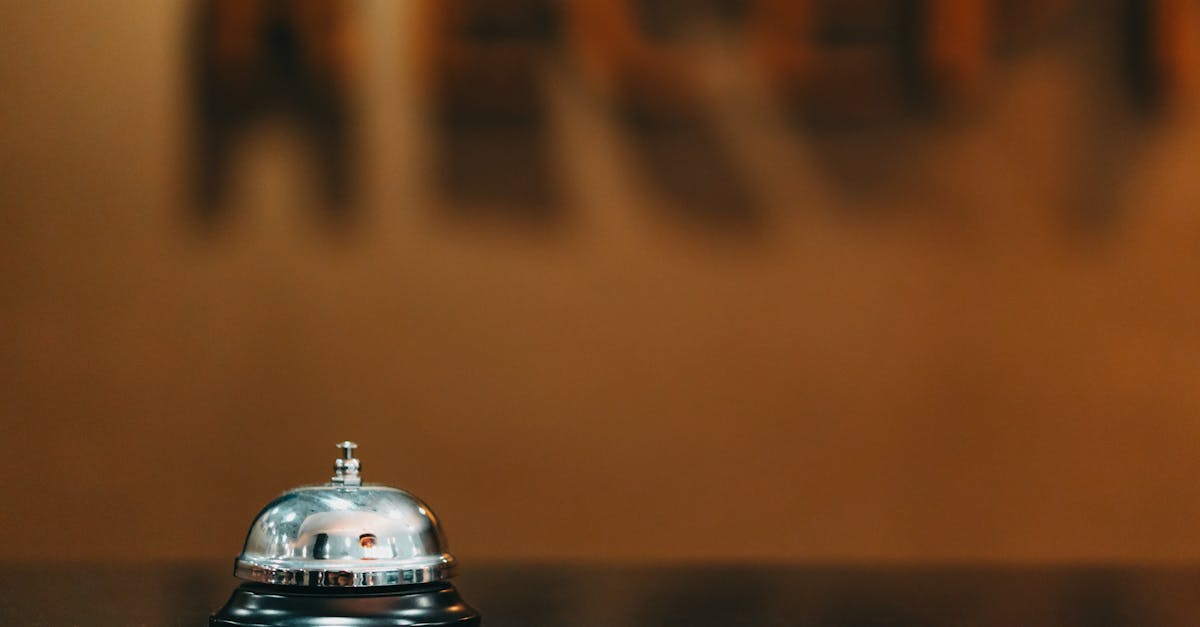 Close-up image of a silver hotel bell on a black surface with 'RECEPTION' blurred in the background.